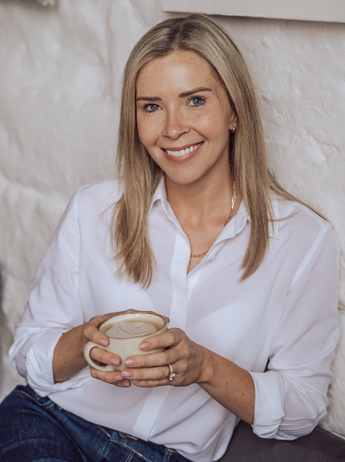 Sophie, senior HR leader and certified coach, smiling while holding a coffee.