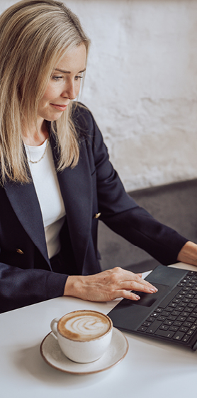 Sophie, founder of Lumera Leadership, typing at her desk with a coffee.
